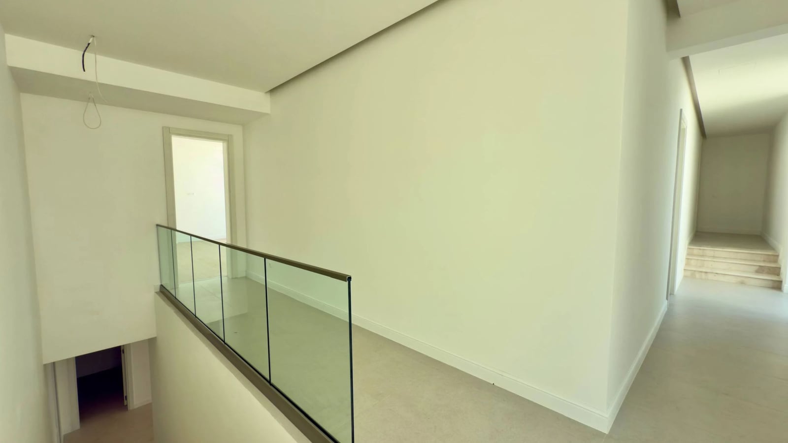 Heller Flur mit Treppe und Glasgeländer in einer Villa in Krašići, Montenegro. Moderne Innenausstattung.