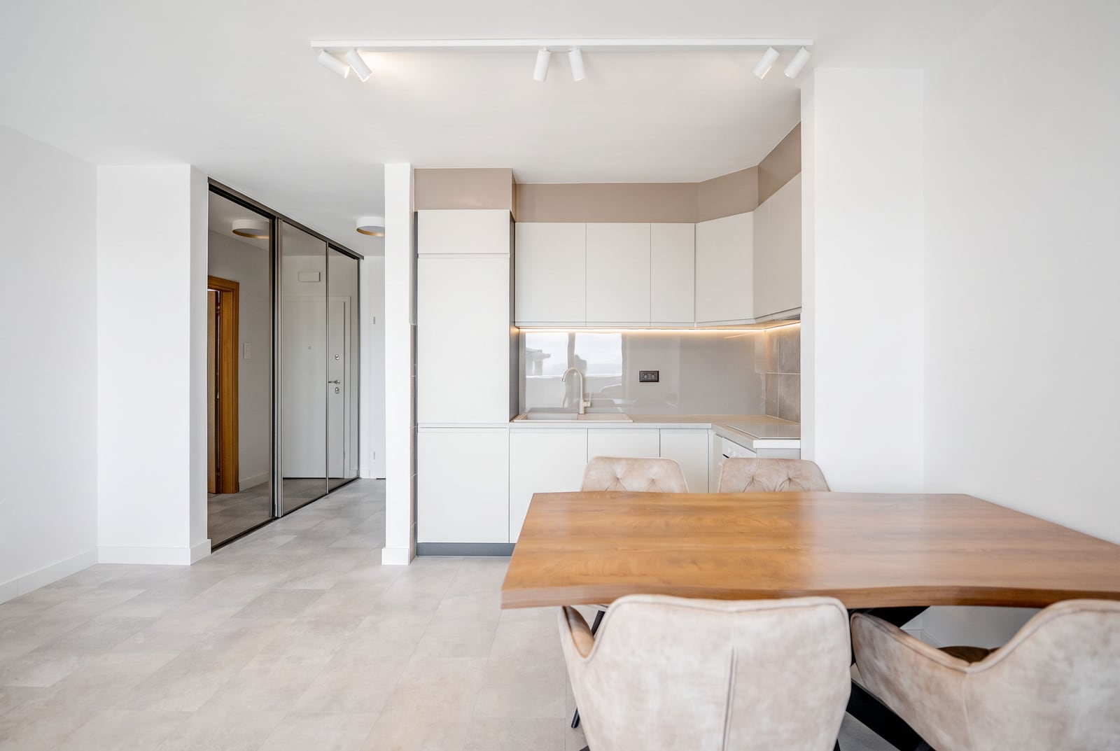 Modern kitchen-living room with white cabinetry and a wooden table in an apartment, Sveti Stefan, Montenegro.