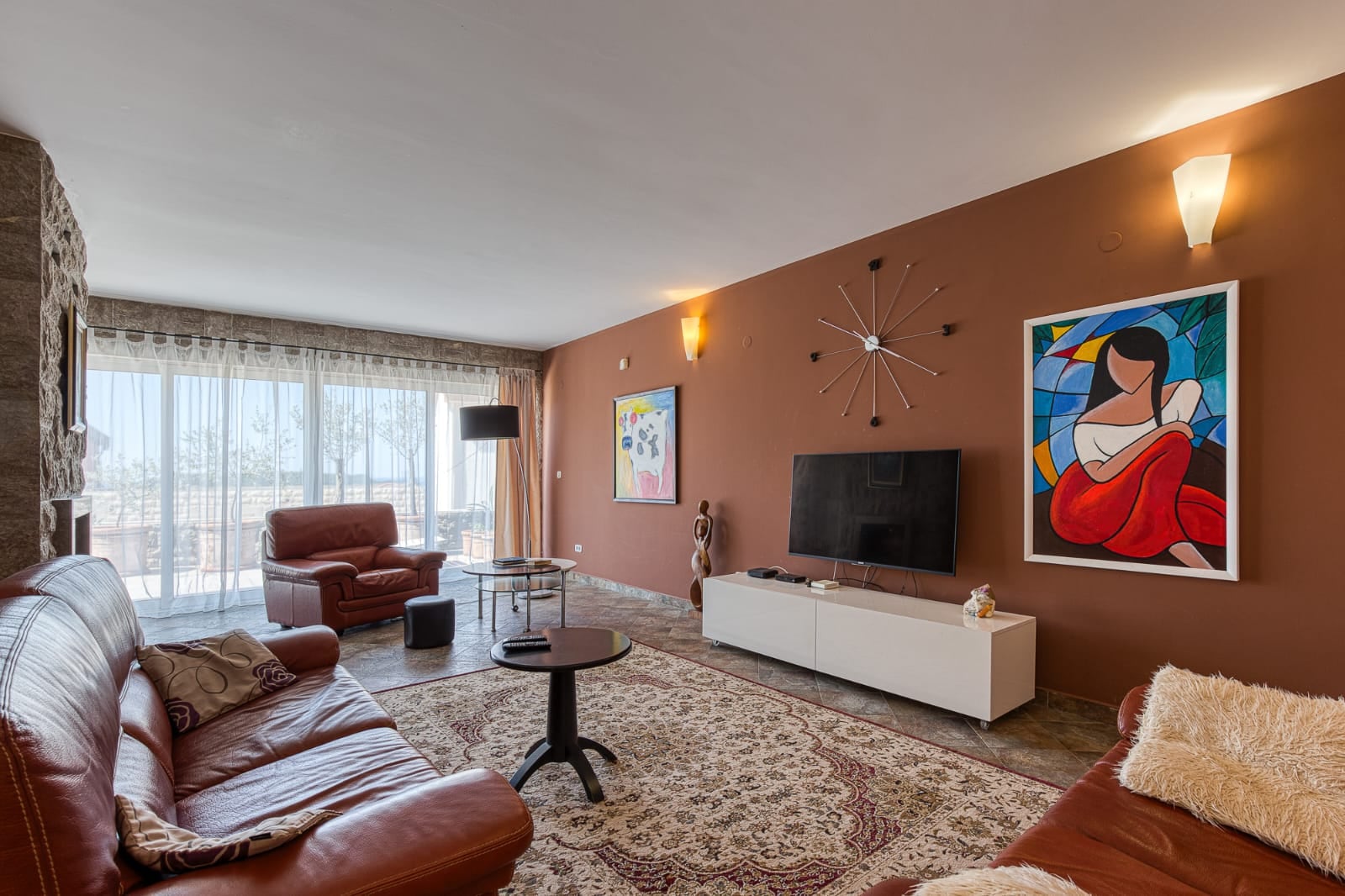 Salon d'une villa à Bečići, Monténégro : mobilier en cuir, baies vitrées, finitions en pierre et décoration de style moderne.