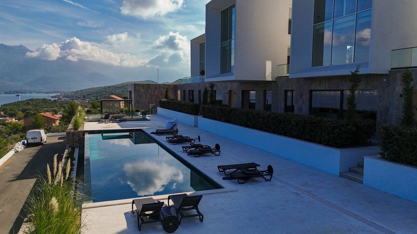 Moderne Villa mit Pool und Meerblick in Krašići, Montenegro: Terrasse mit Liegestühlen und Panoramablick.