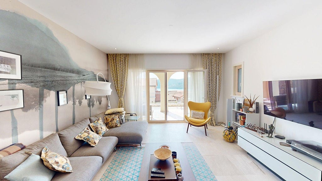 Moderna dnevna soba u stanu u Luštici, Crna Gora: sivi sofa, žuta fotelja, panoramski pogled na more i terasu.