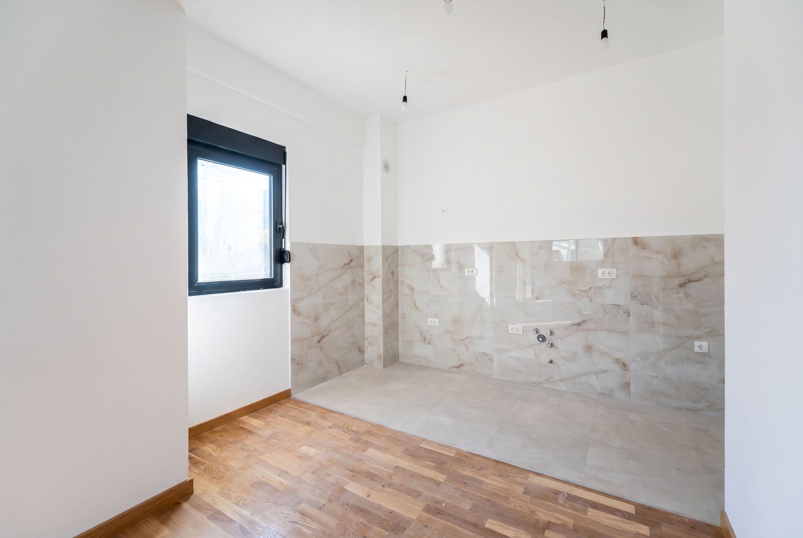 Kitchen area in a new apartment in the city of Bar, Montenegro: marble-look tile finish, parquet flooring, and a window.