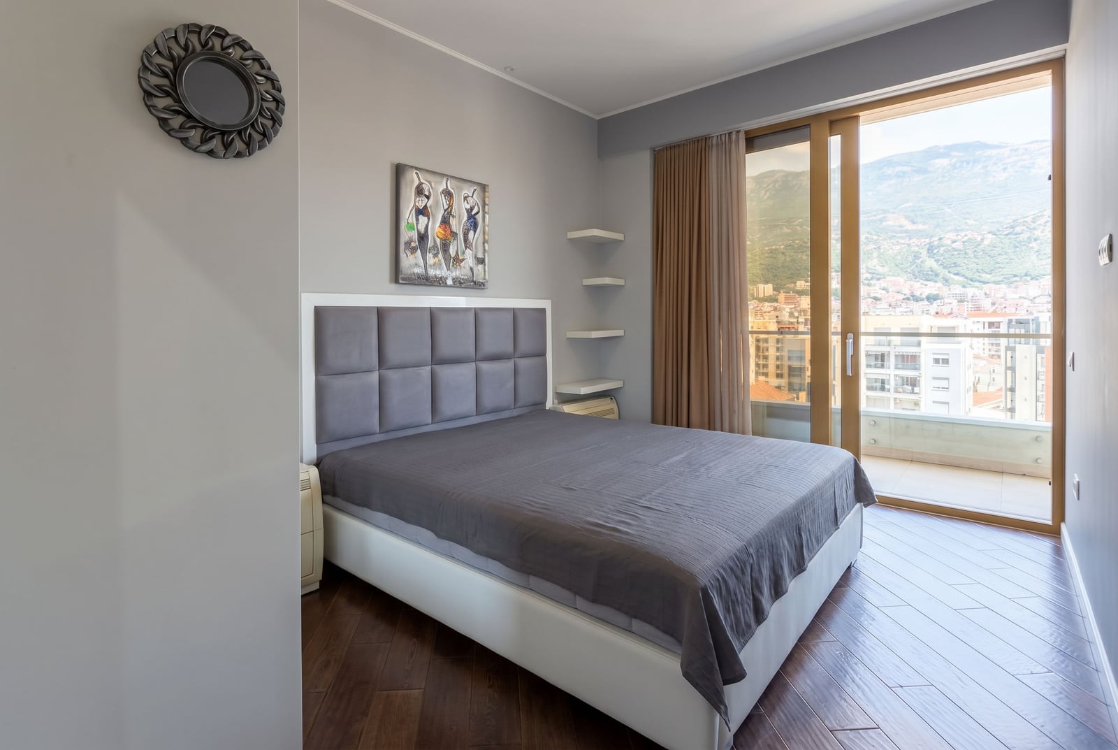 Modern bedroom with a double bed and panoramic views of the mountains and the city of Budva, Montenegro.
