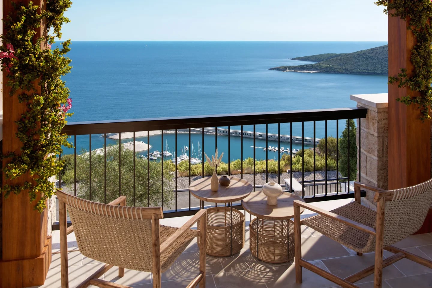 Terrasse mit Meerblick und Blick auf die Marina im Wohnkomplex Luštica, Montenegro: Korbmöbel und Steinverkleidung.