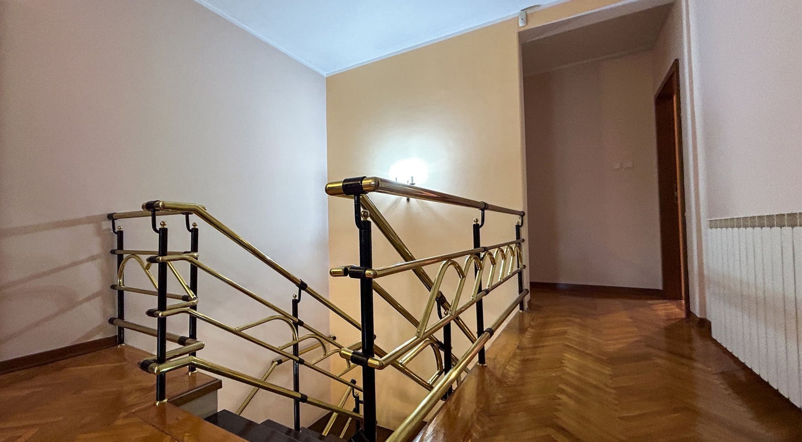Treppe mit goldfarbenem Geländer im Interieur einer Villa in Dobrota, Montenegro: Parkettboden und helle Wandgestaltung.