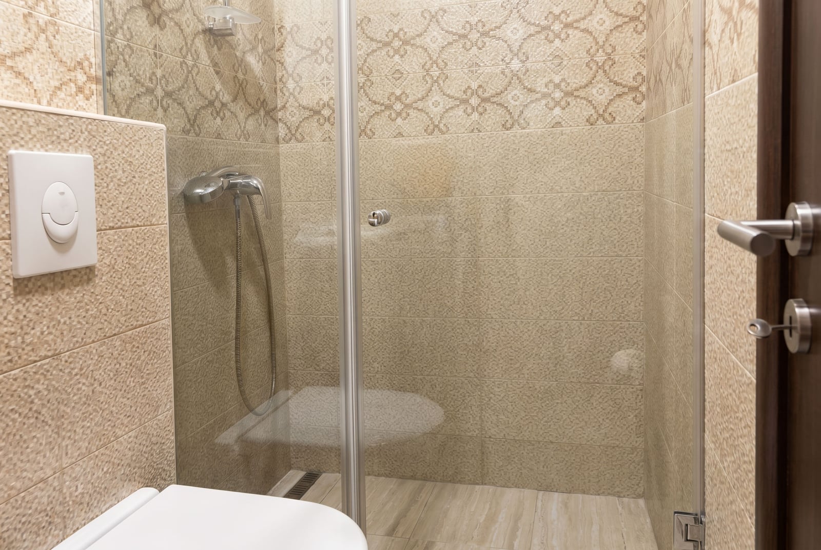 Moderno kupatilo sa tuš kabinom i bež pločicama u stanu na prodaju, Budva, Crna Gora.
