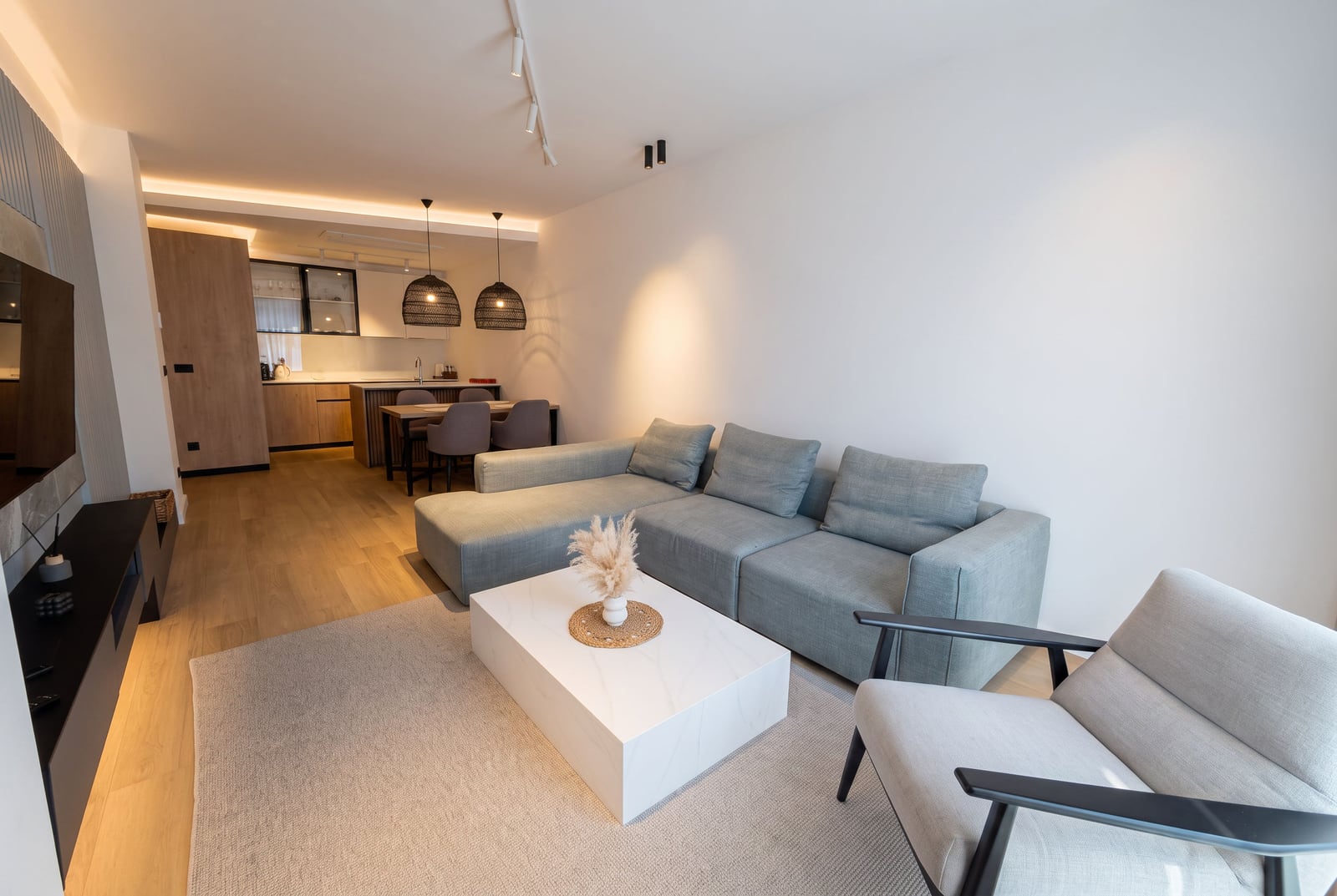 Modern living room with a soft sofa, coffee table, and an open-plan kitchen in an apartment in Budva, Montenegro.