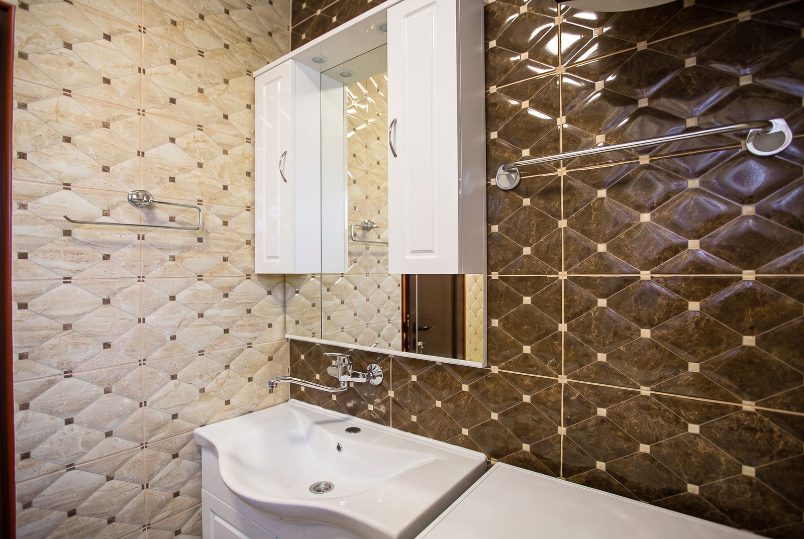 Modern bathroom in an apartment in Budva, Montenegro: white sink, mirrored cabinet, and tiled finish.
