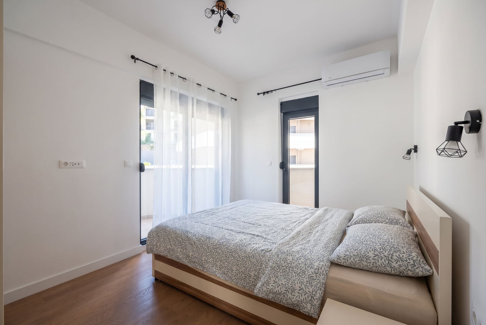 Svetla spavaća soba sa bračnim krevetom i izlazom na balkon u stanu u Bečićima, Crna Gora