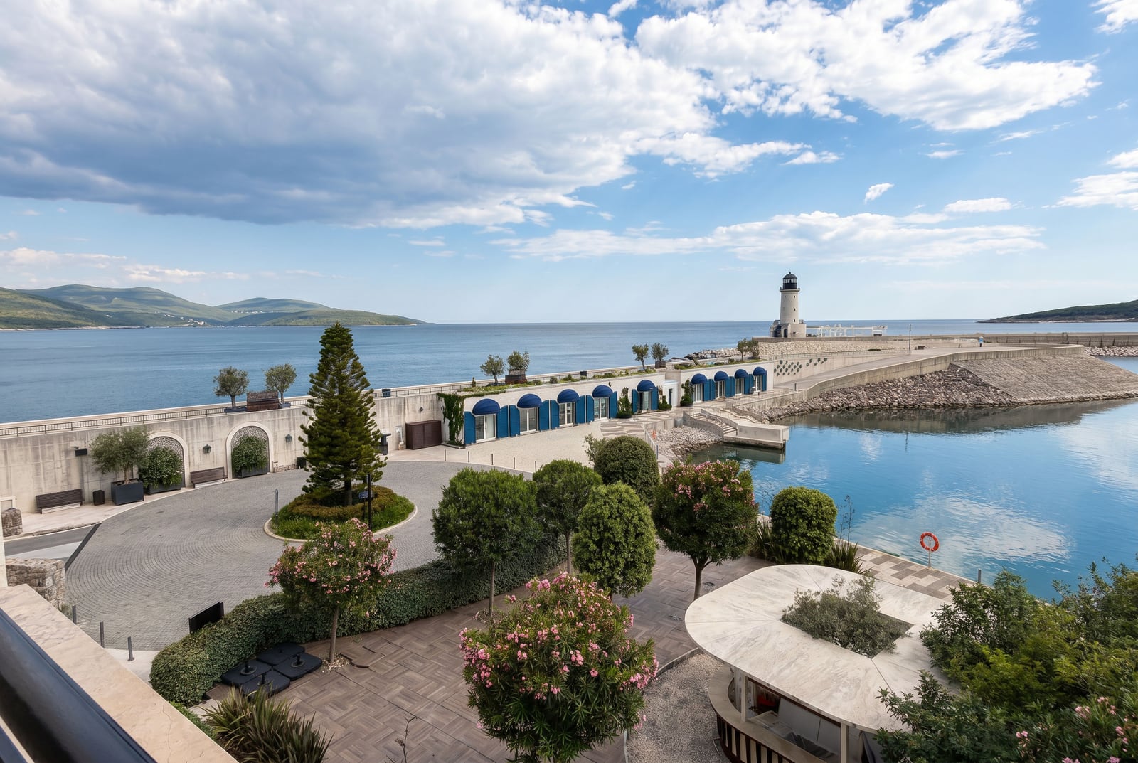 Blick auf die Promenade und den Leuchtturm in Luštica Bay, Montenegro: gepflegtes Gelände mit Landschaftsgestaltung und Meerblick.