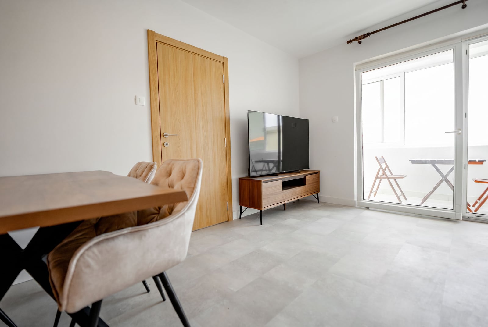 Living room in an apartment in Sveti Stefan, Montenegro: modern furniture, TV area, dining table, and access to the balcony.