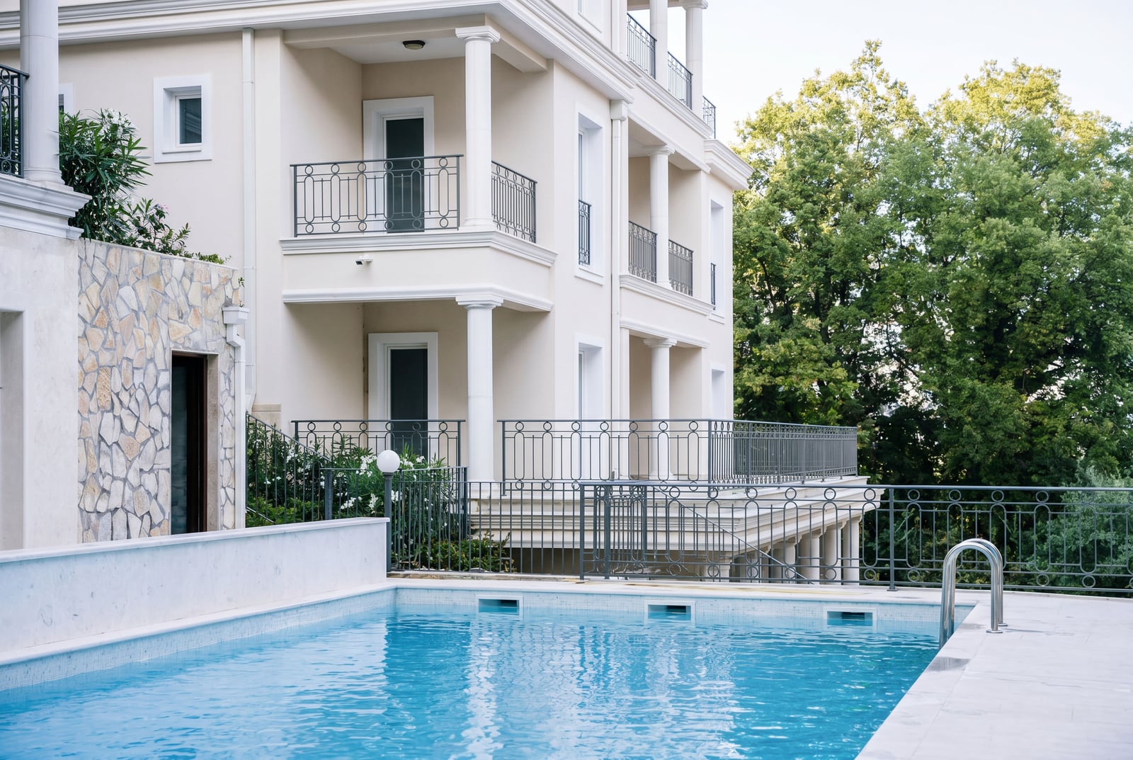 Outdoor swimming pool at a luxury villa with columns and terraces in Kumbor, Montenegro. Modern stone finish.