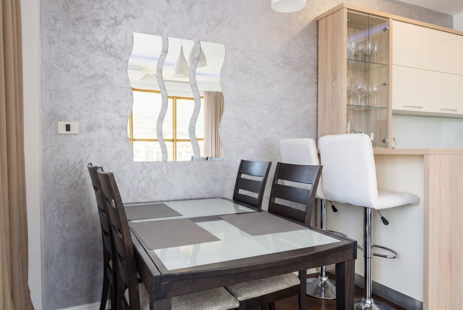 Modern kitchen-dining room in a Budva apartment, Montenegro: dining table, breakfast bar, and decorative mirror.