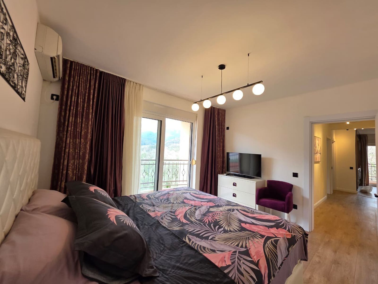 Udobna spavaća soba sa bračnim krevetom i izlazom na balkon u stanu u Bečićima, Crna Gora. Moderan enterijer.