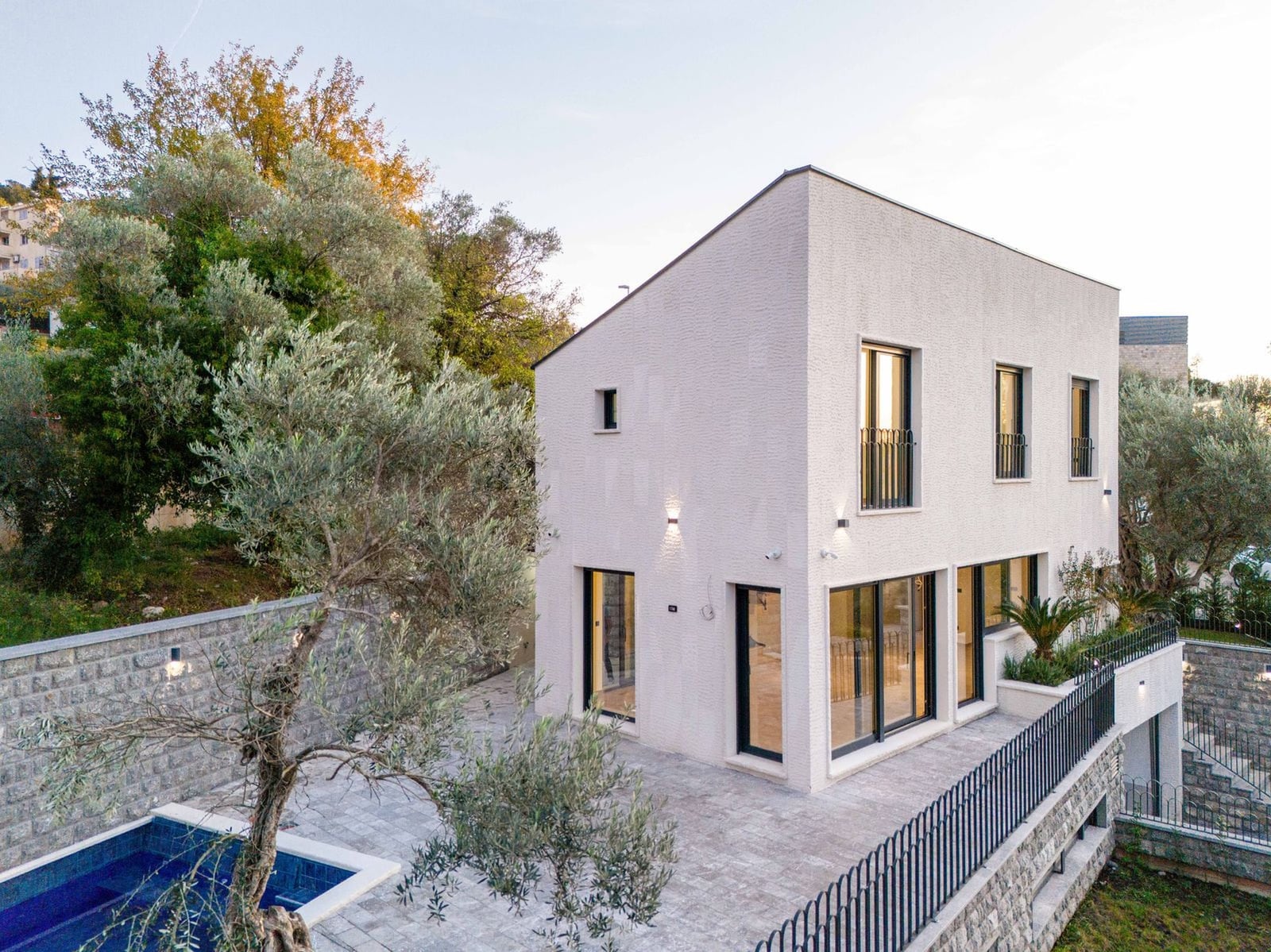 Villa moderne à deux étages avec piscine et terrasse à Kamenovo, Monténégro : façade en pierre blanche et fenêtres panoramiques.