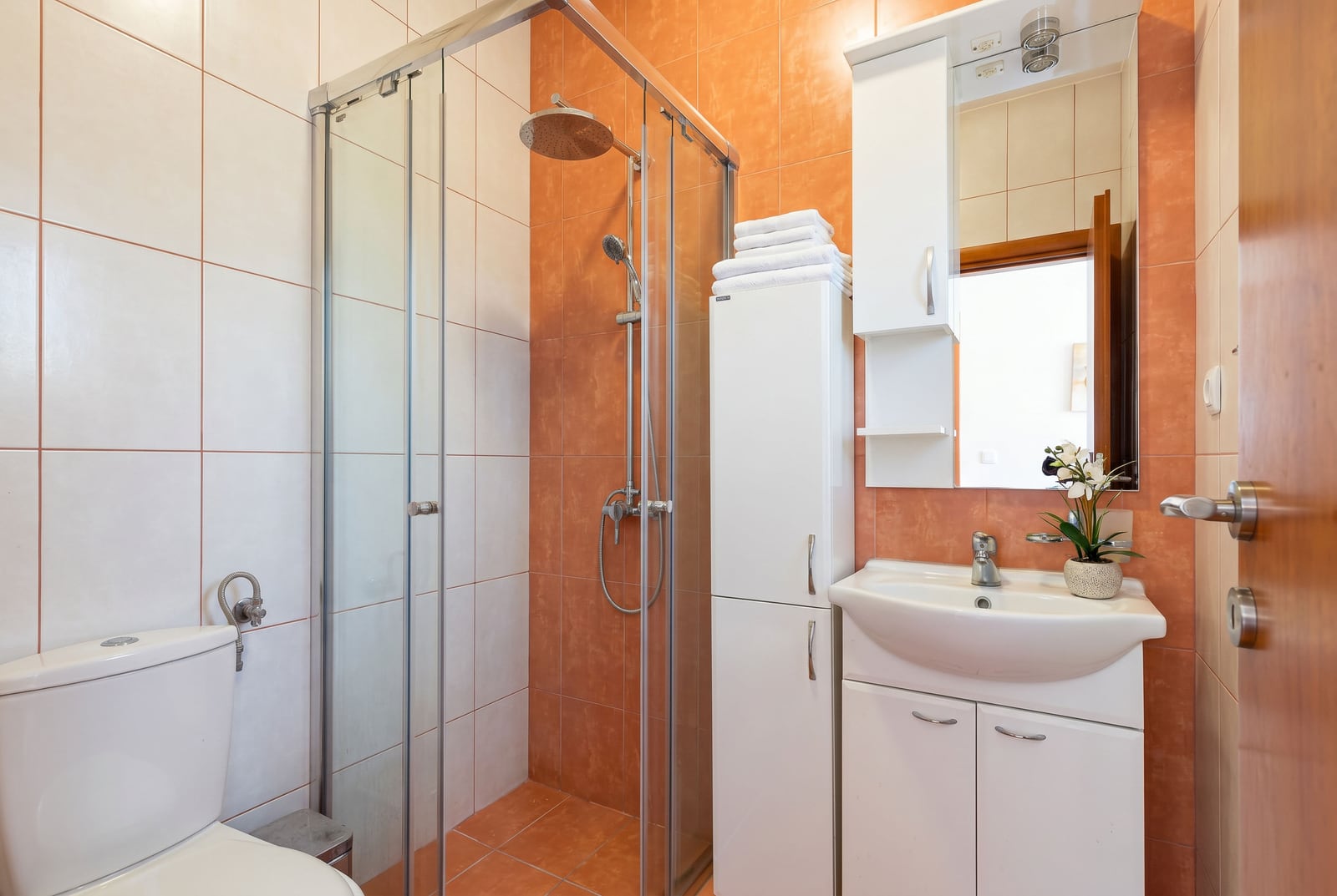 Salle de bain avec cabine de douche et mobilier blanc dans une villa à Bečići, Monténégro. Finitions modernes en carrelage.