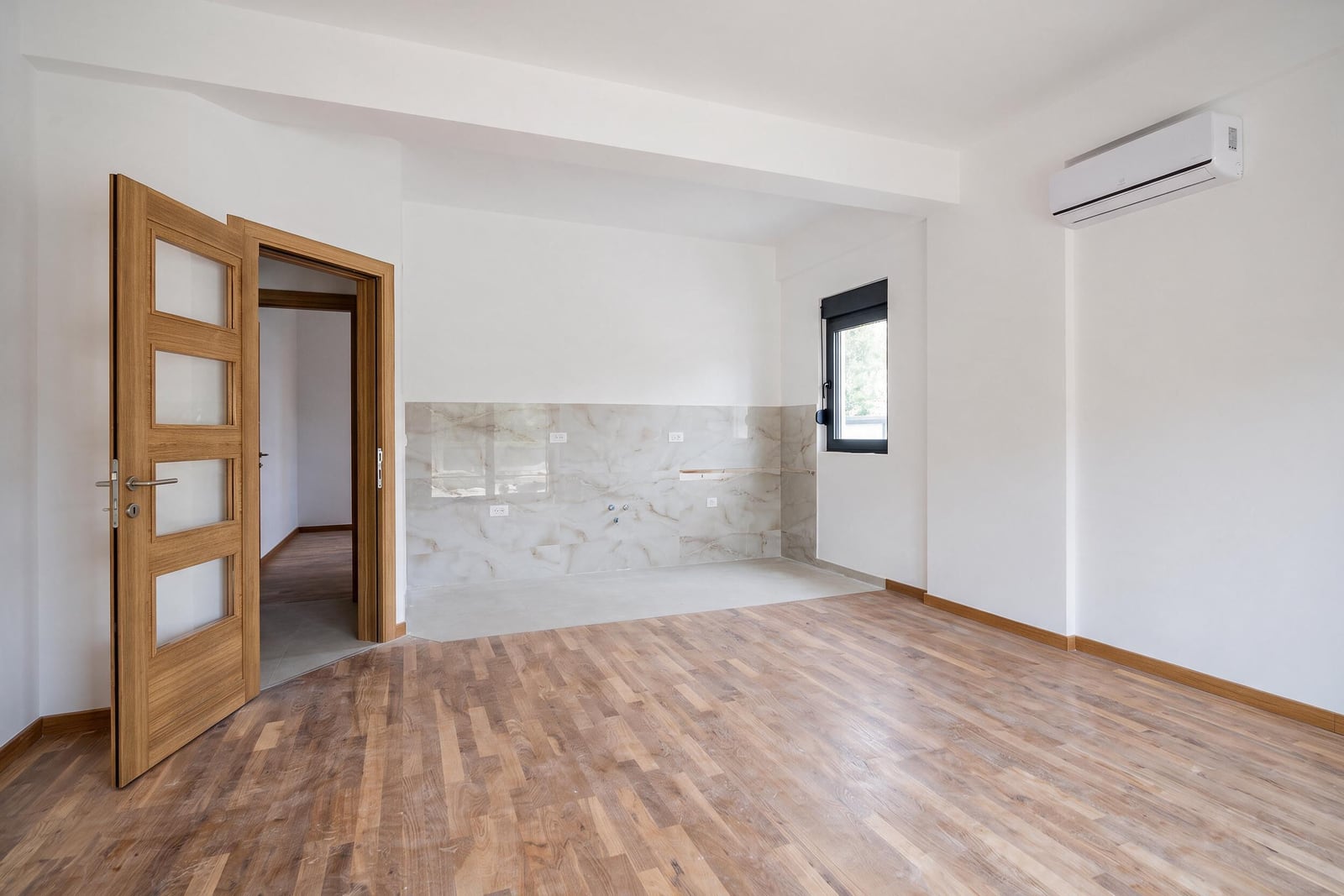 Bright kitchen in an apartment in the city of Bar, Montenegro: laminate flooring, porcelain tile backsplash, interior door, and air conditioner.