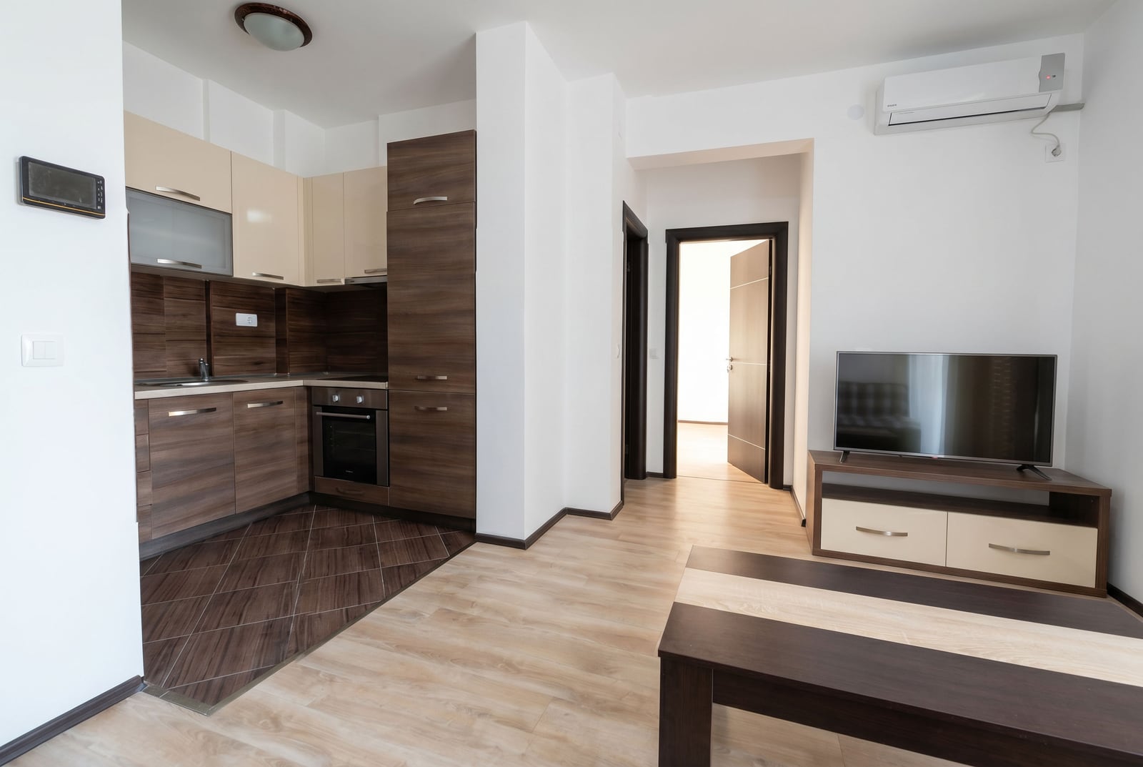 Modern open-plan kitchen and living room with furniture in a Budva apartment, Montenegro: built-in appliances, TV area, and bright interior.