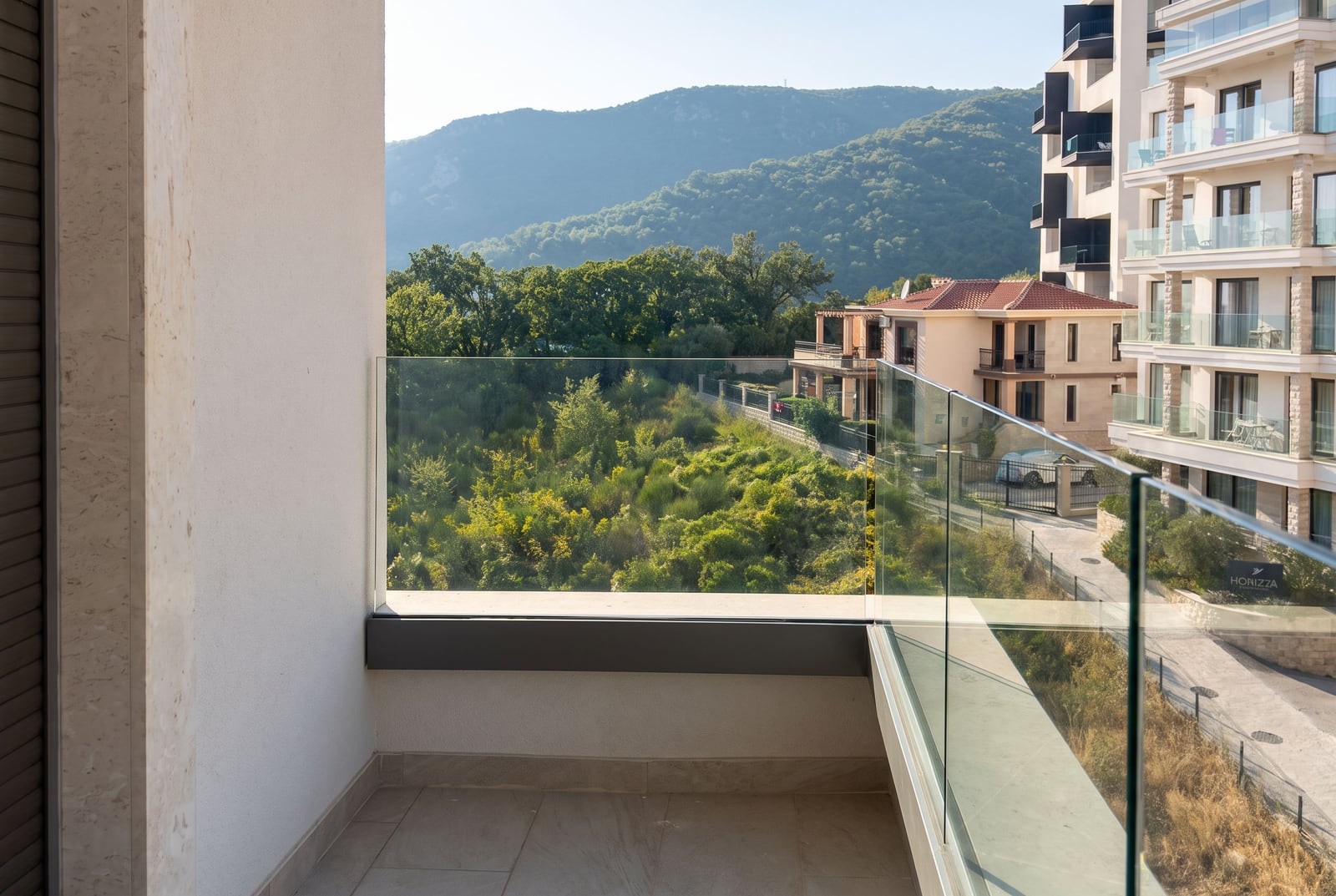 Balcony with panoramic glass railing and mountain views in a residential complex in Becici, Montenegro