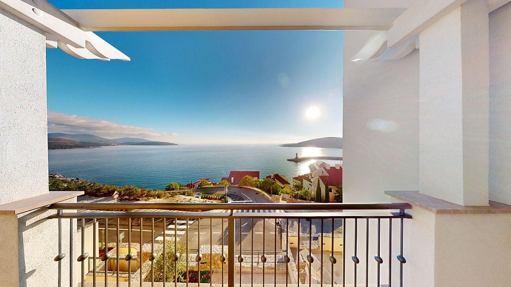 Blick vom Balkon der Wohnung in Luštica Bay, Montenegro: Panorama der Adria, der Uferpromenade und der Berge an einem sonnigen Tag.