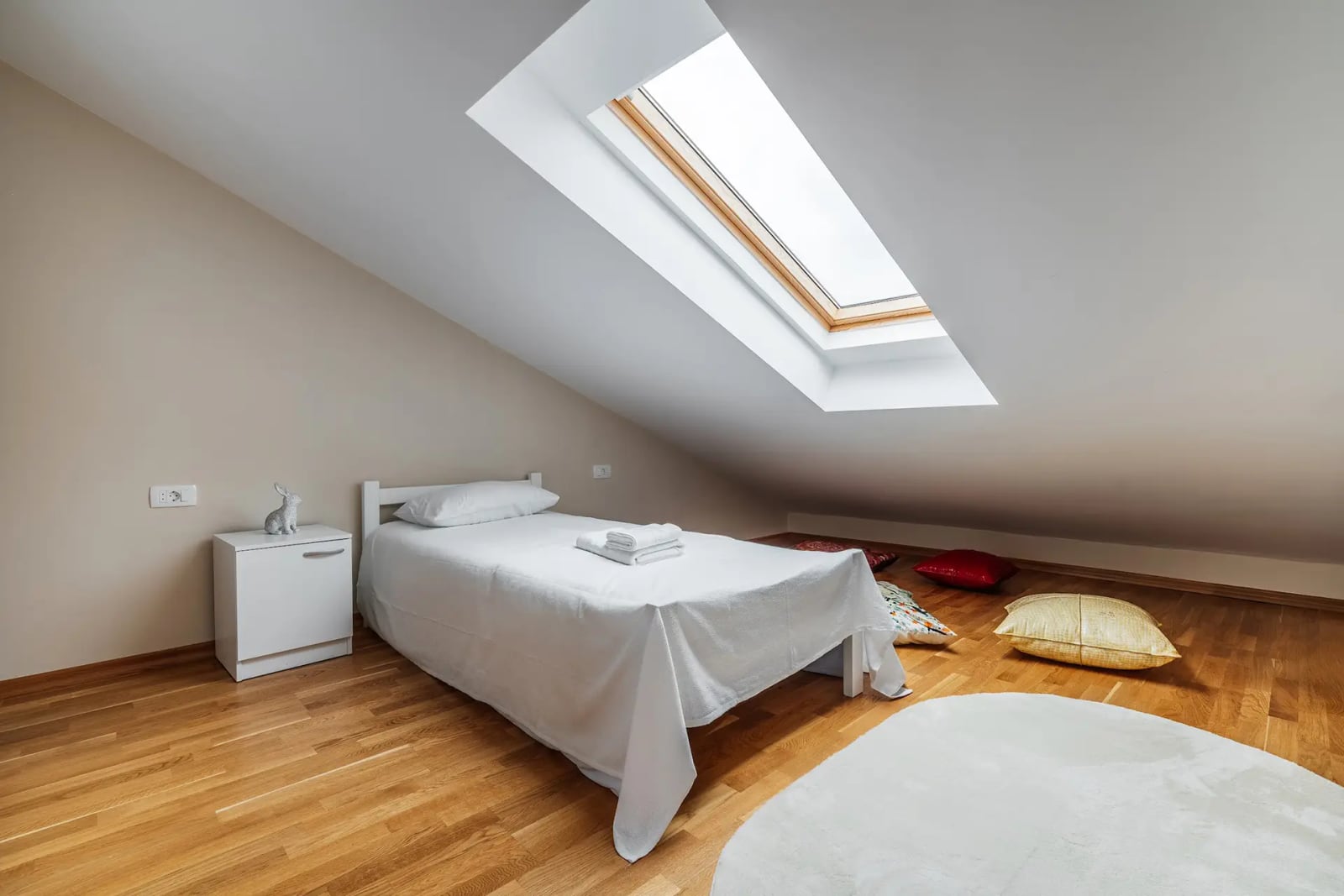 Cozy attic bedroom with a bed and skylight in a villa in Reževići, Montenegro. Parquet flooring and bright interior.