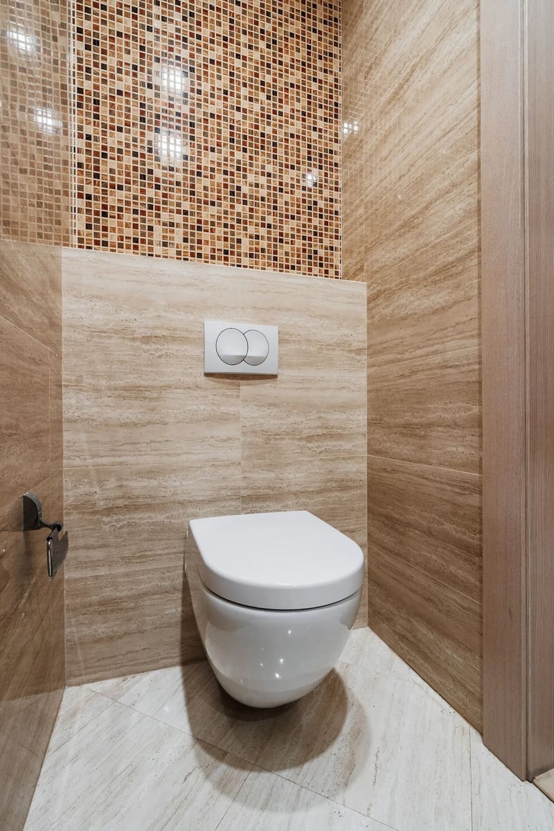 Moderan sanitarni čvor sa visećom WC šoljom i oblogom od bež pločica i mozaika u stanu, Budva, Crna Gora.