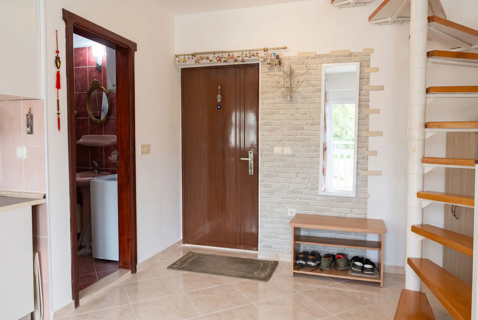 Entryway featuring a main door, shoe bench, spiral staircase, and an open bathroom doorway.