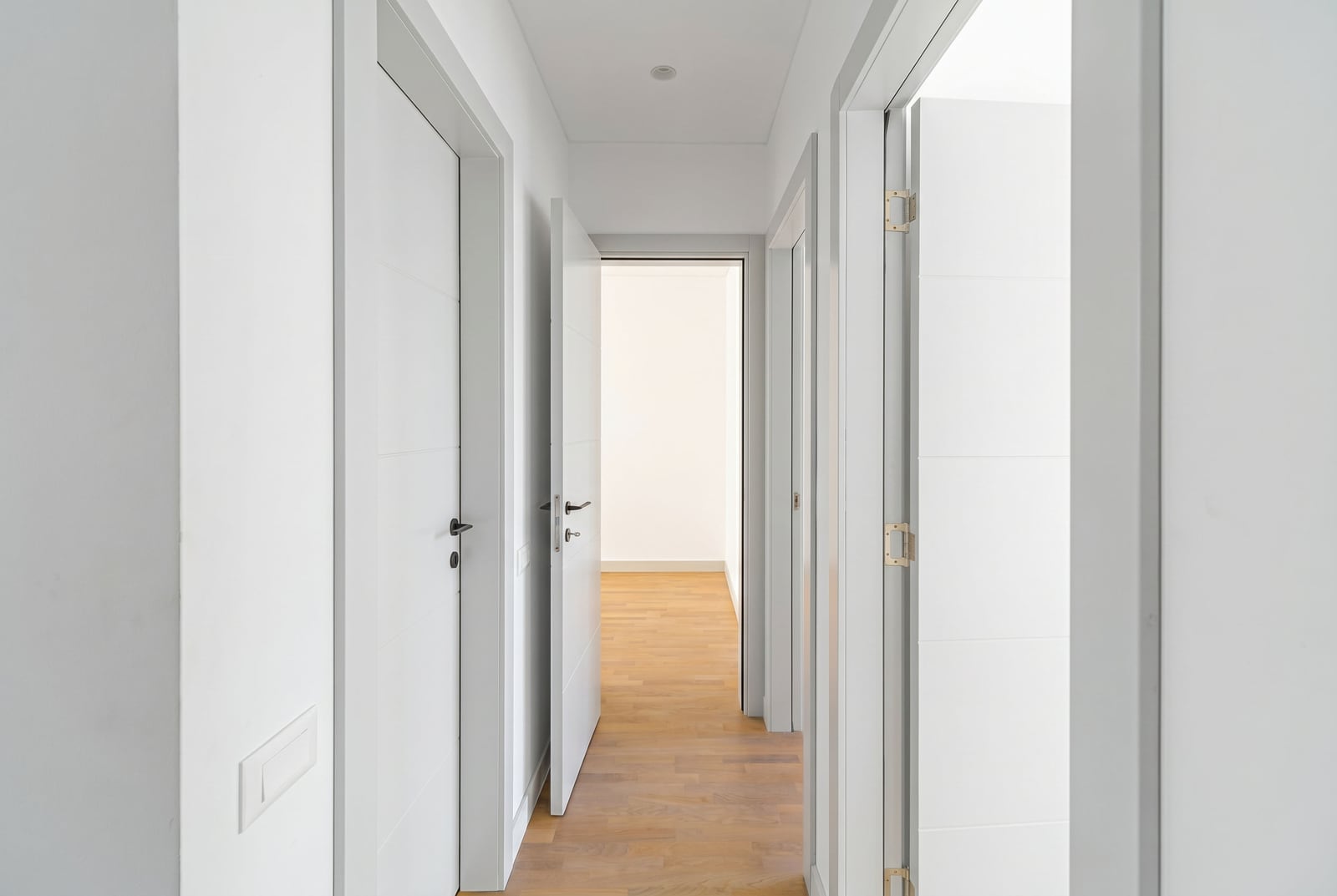 Kavaç, Karadağ'daki bir townhouse'da beyaz iç kapıları ve parke zemini olan aydınlık koridor.
