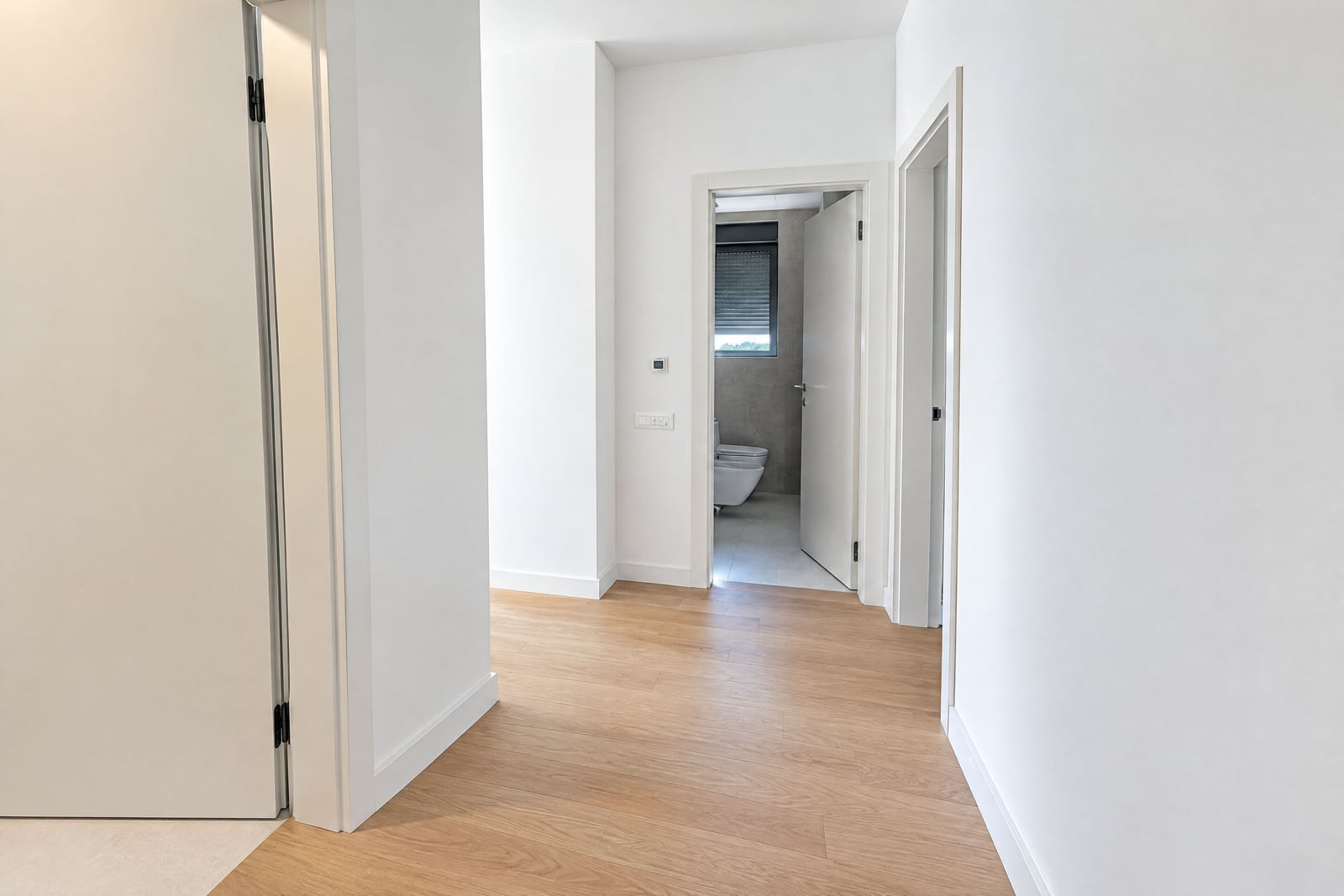 Couloir lumineux avec parquet et murs blancs dans un appartement neuf à Bečići, Monténégro