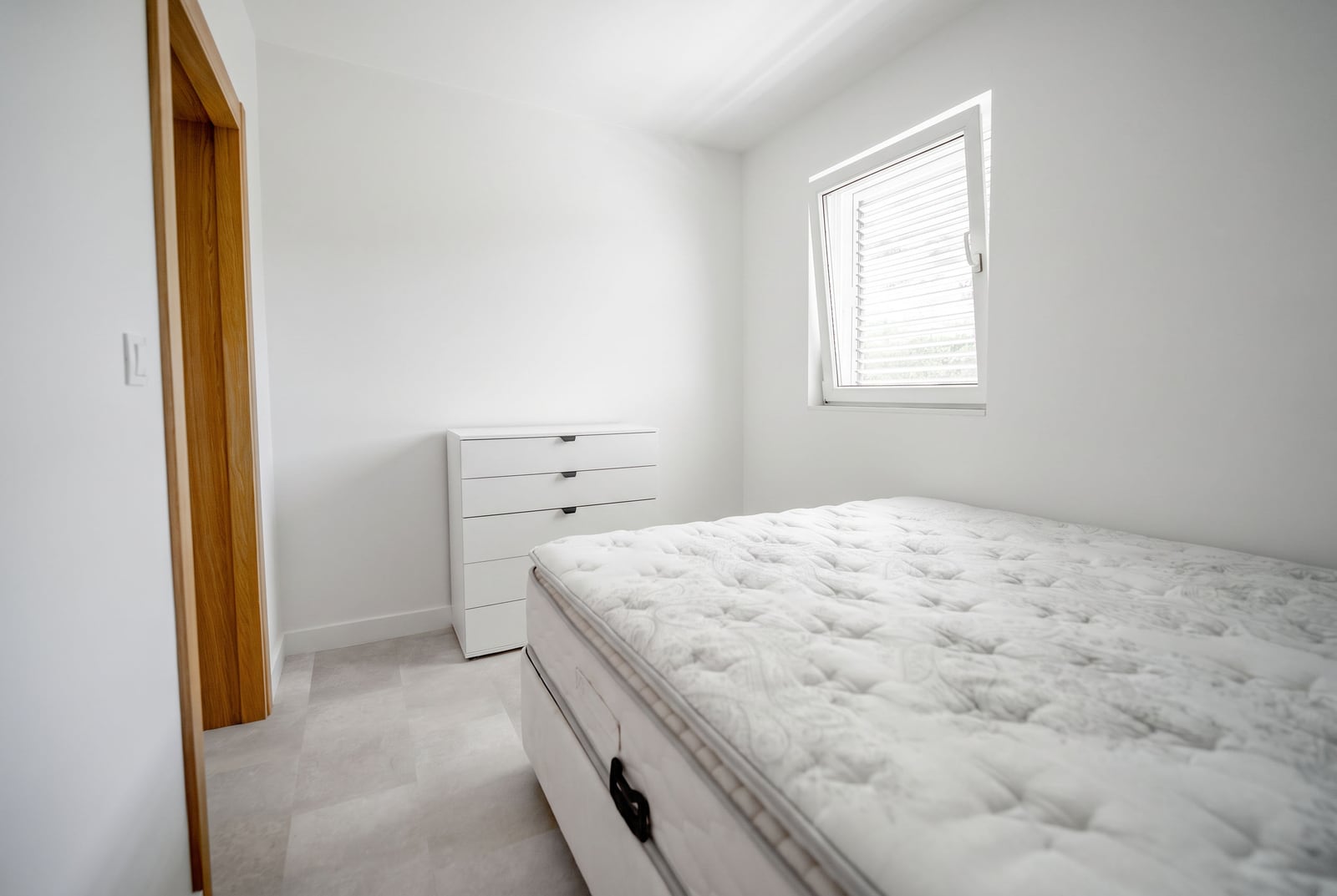 Bright bedroom with a white dresser and bed in an apartment at the Sveti Stefan resort, Montenegro. Modern interior.