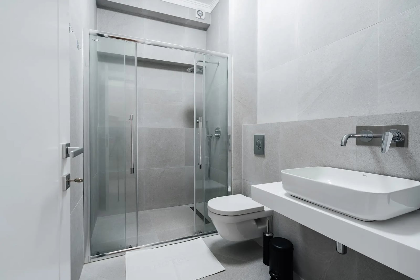 Modern bathroom with a walk-in shower in a villa in Reževići, Montenegro: light-colored tiles and fixtures.