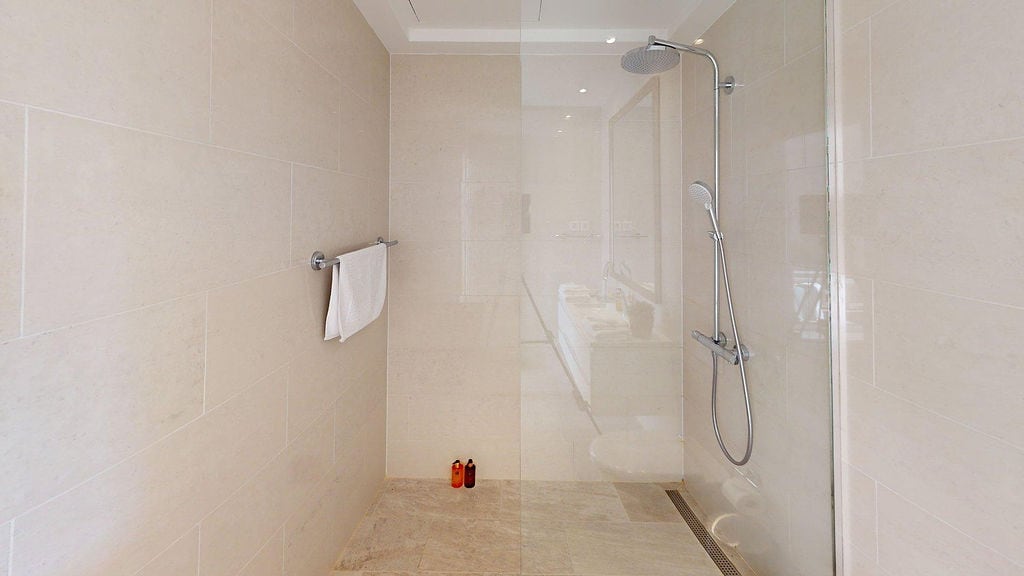 Modernes Duschkabinendesign mit beigen Fliesen in einer Wohnung in Luštica, Montenegro: stilvolles Badezimmerinterieur.