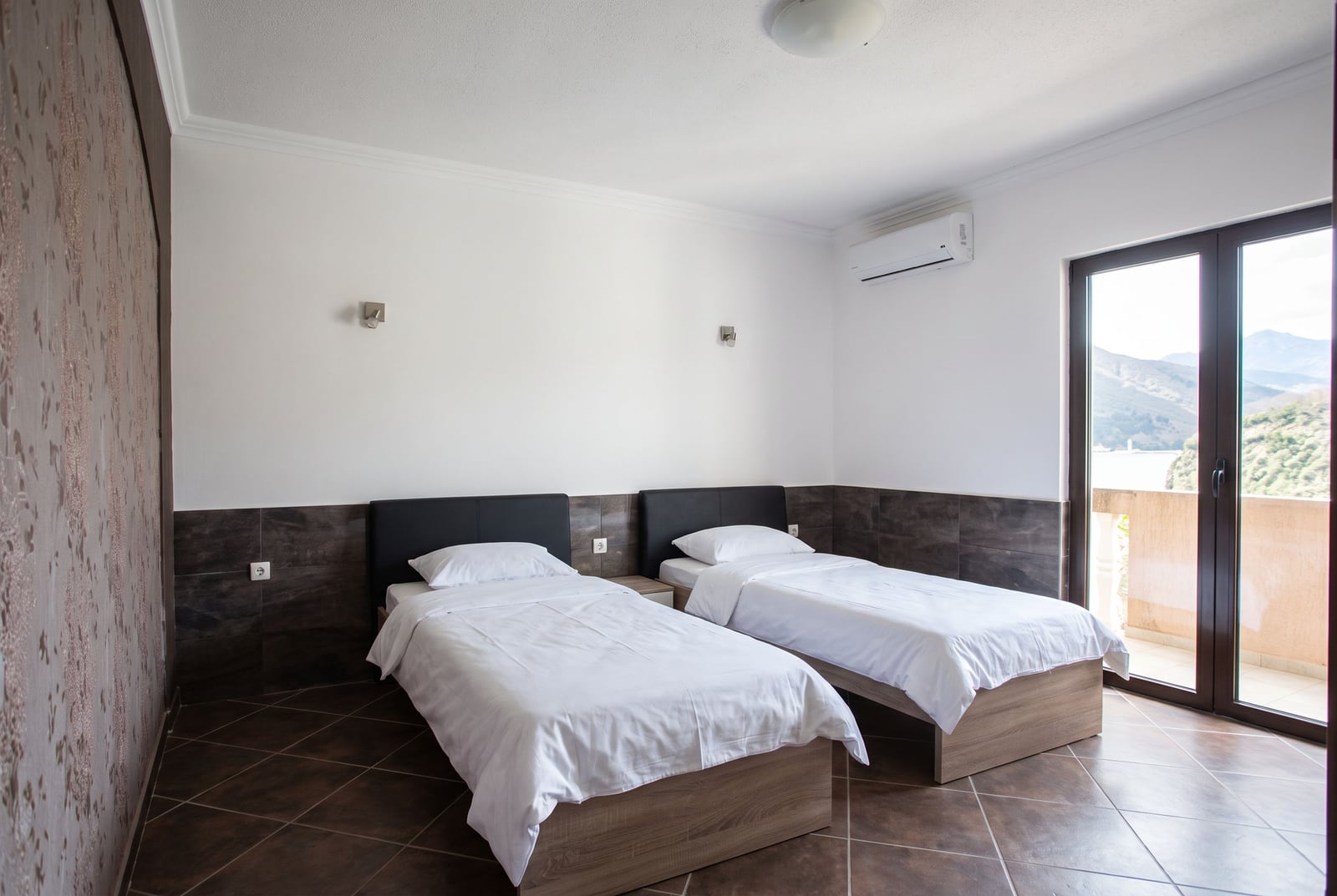 Bright bedroom with two single beds, air conditioning, and balcony access in a house in Tivat, Montenegro.