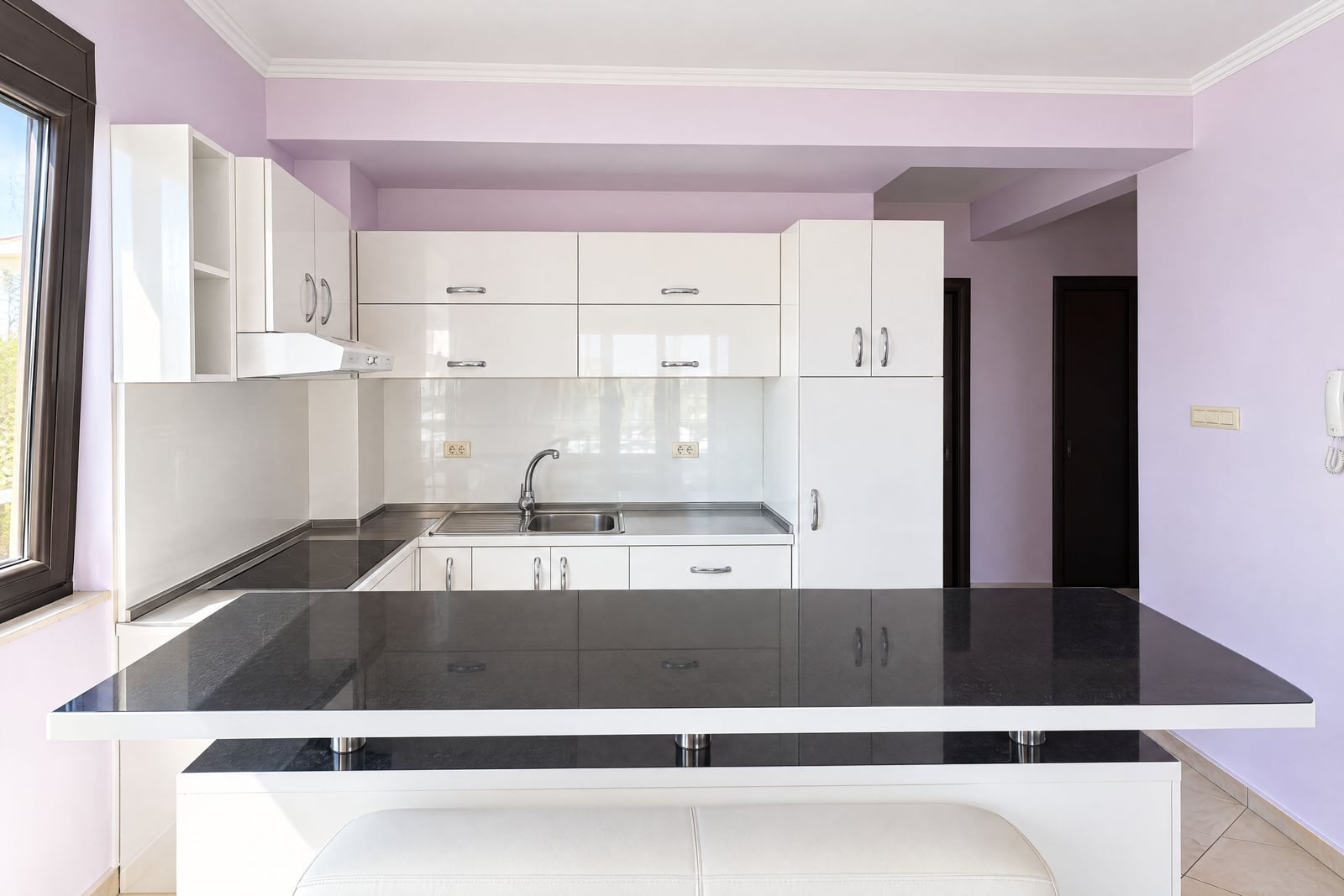 White kitchen with glossy facades and a black bar counter in an apartment in Budva, Montenegro