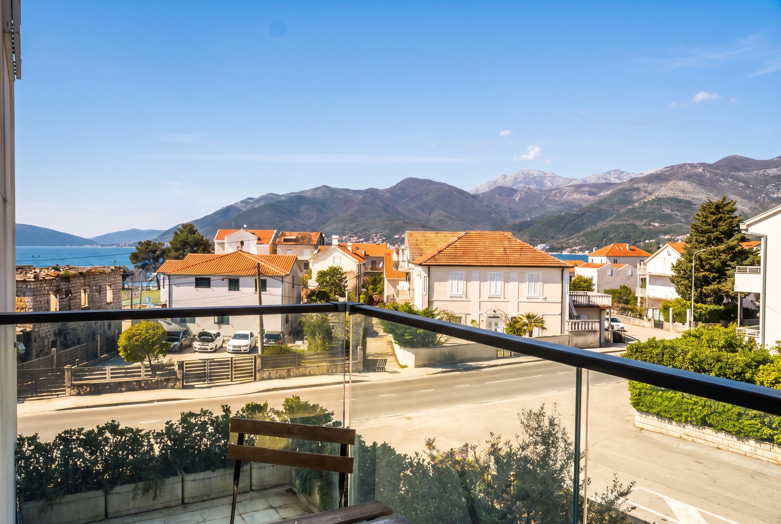 Panoramski pogled sa balkona stana u Tivtu, Crna Gora: planine, more i krovovi od crepa.