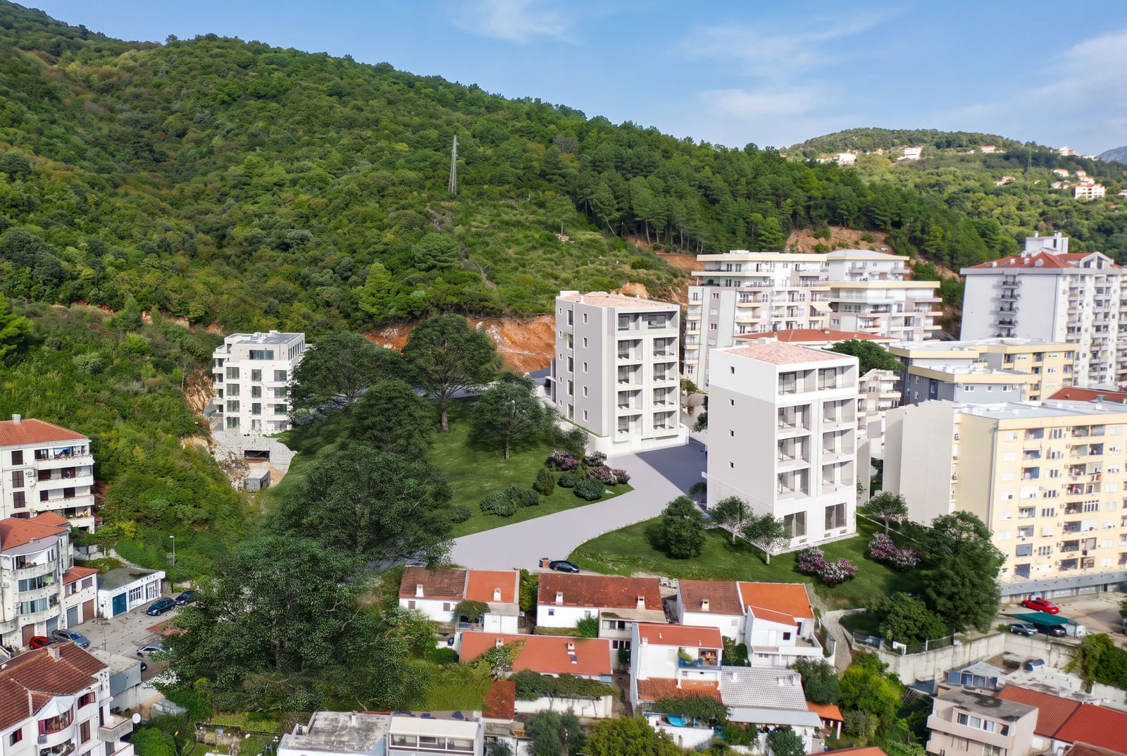Aerial view of a residential complex under construction in Budva, Montenegro: modern buildings amidst greenery and mountain landscape.