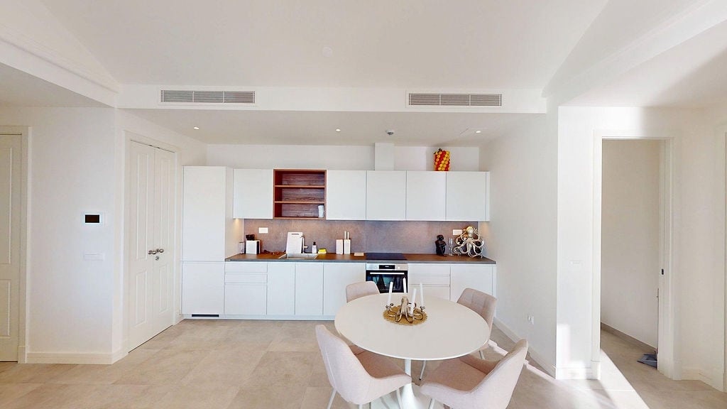 Moderne weiße Küche mit Essbereich in der Wohnung Lustica Bay, Montenegro: Einbaugeräte und helles Design.