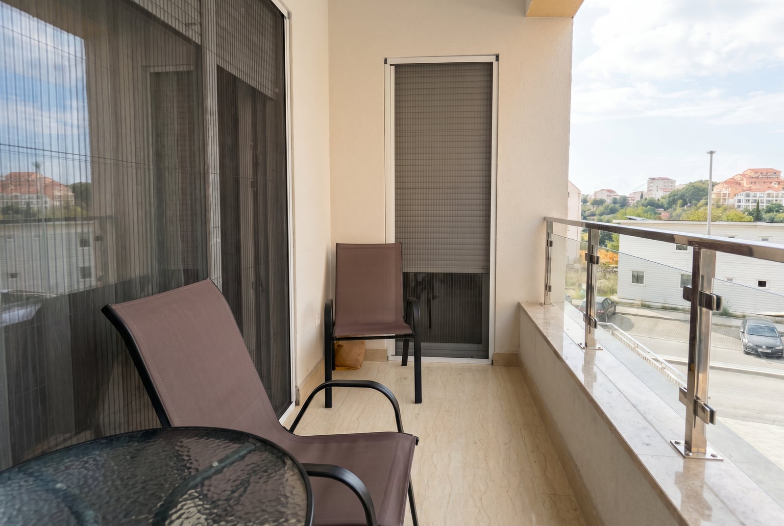 Balkon sa nameštajem i staklenom ogradom u stanu, Bečići, Crna Gora. Pogled na grad i planine, moderna završna obrada.