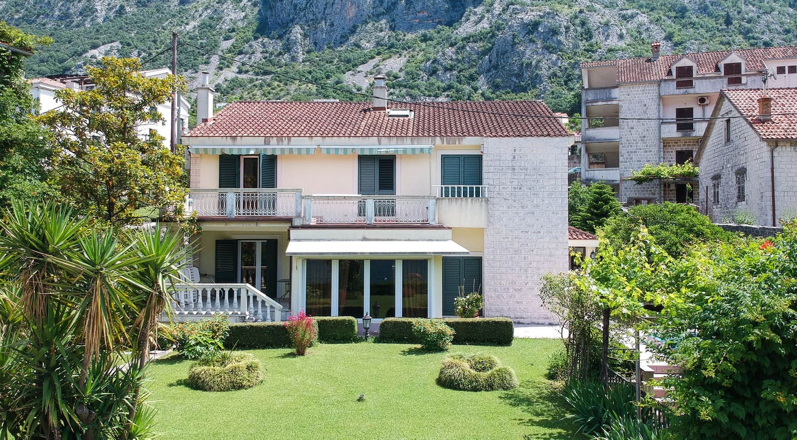 Zweigeschossige Villa in Dobrota, Montenegro: Haus mit Terrasse, Panoramafenstern, grünem Garten und Bergblick.