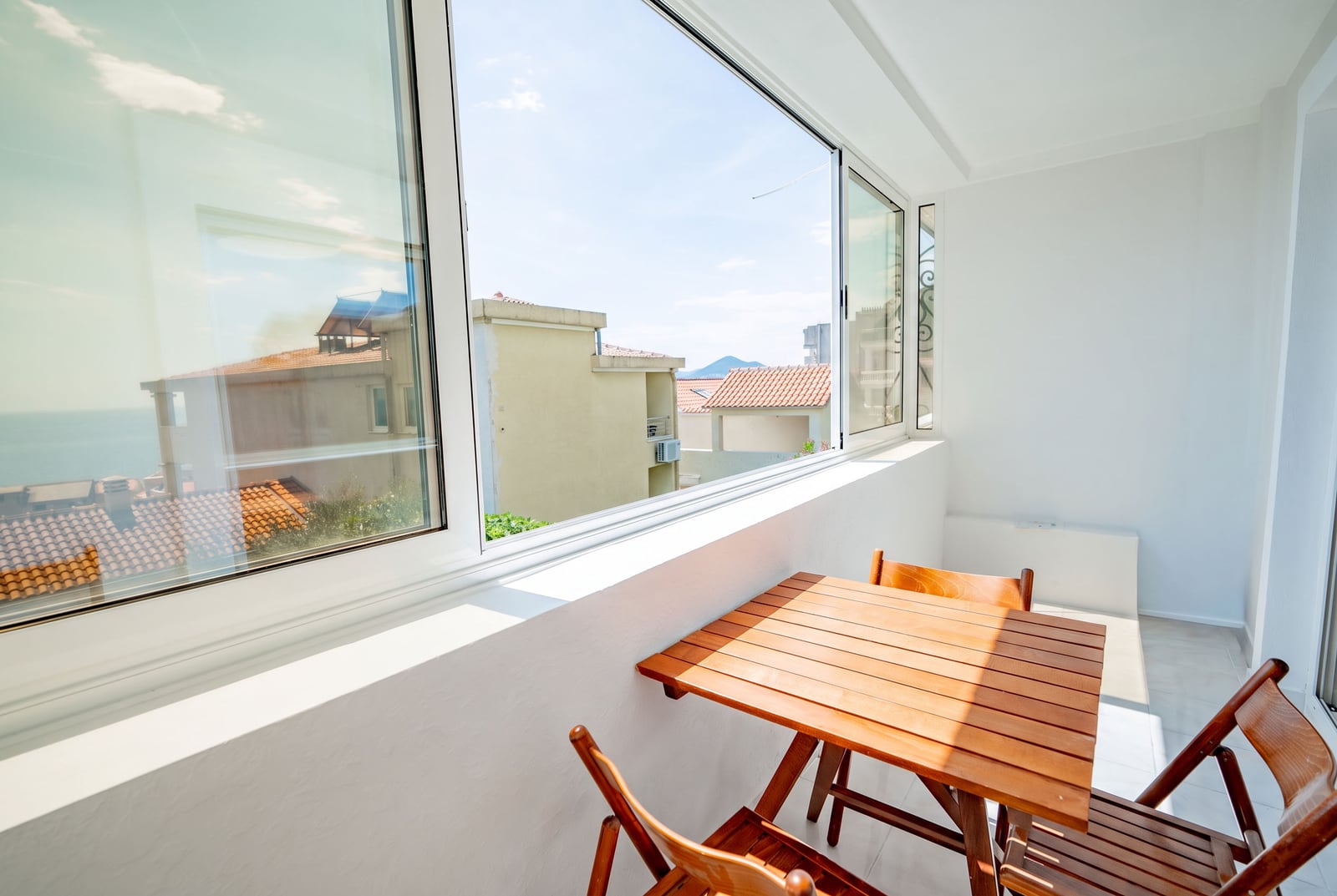 Bright balcony with wooden furniture and sea view in an apartment, Sveti Stefan, Montenegro.