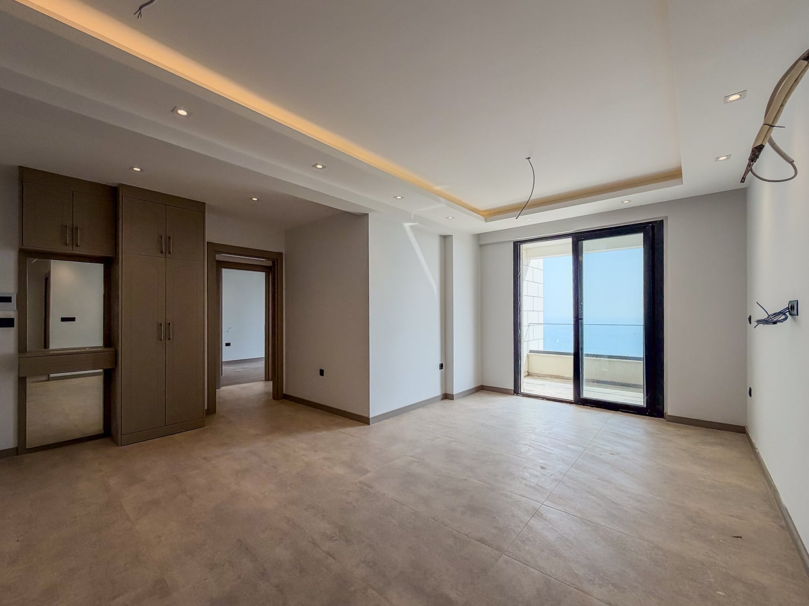New bedroom with finished interior, built-in wardrobe, and panoramic window with sea view in Budva, Montenegro