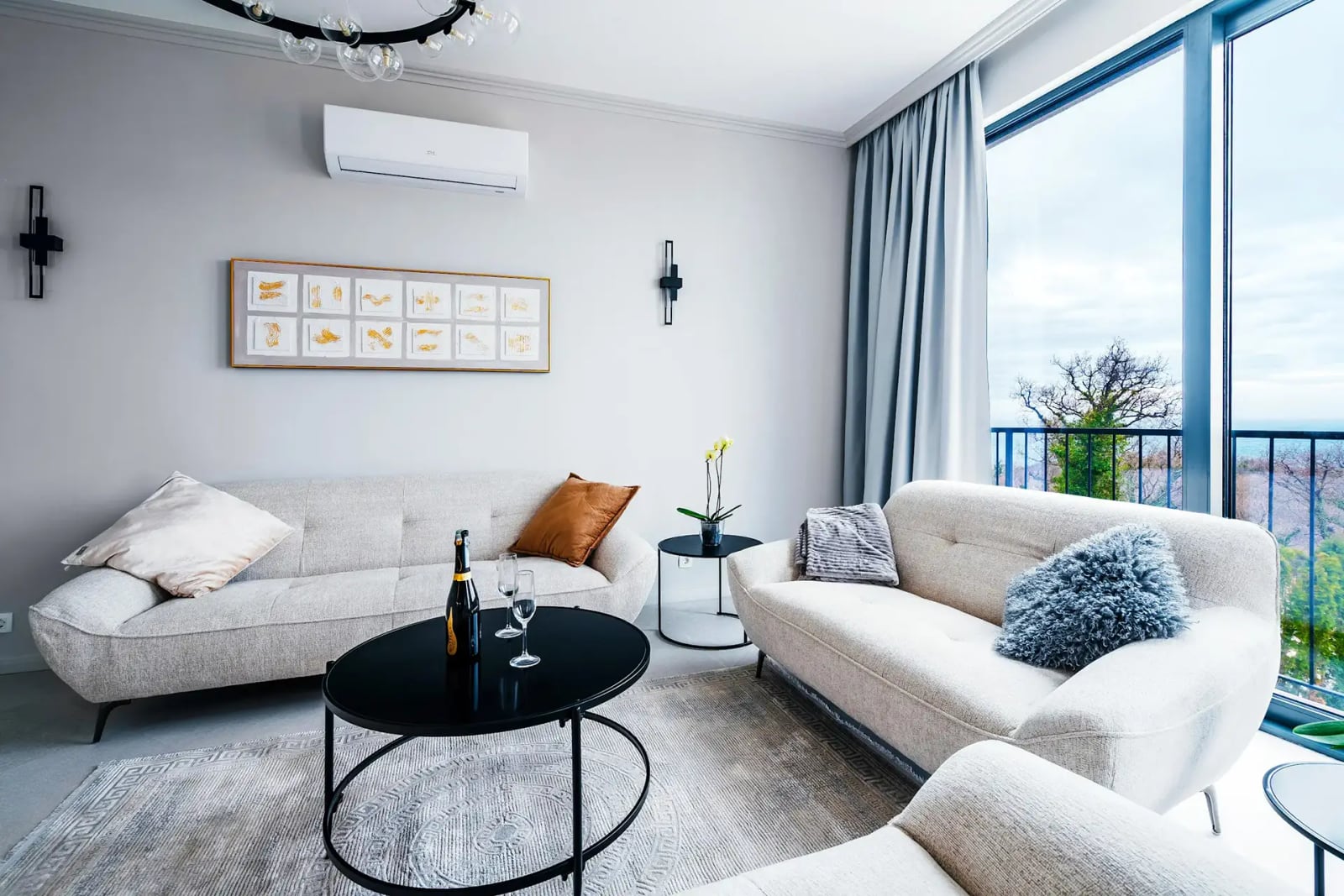 Modern living room in a villa in Reževići, Montenegro: light-colored furniture, panoramic windows with a sea view, and stylish decor.