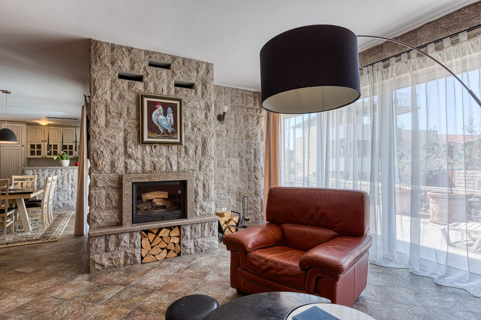 Salon avec cheminée, finitions en pierre et fauteuil en cuir dans une villa à Bečići, Monténégro.