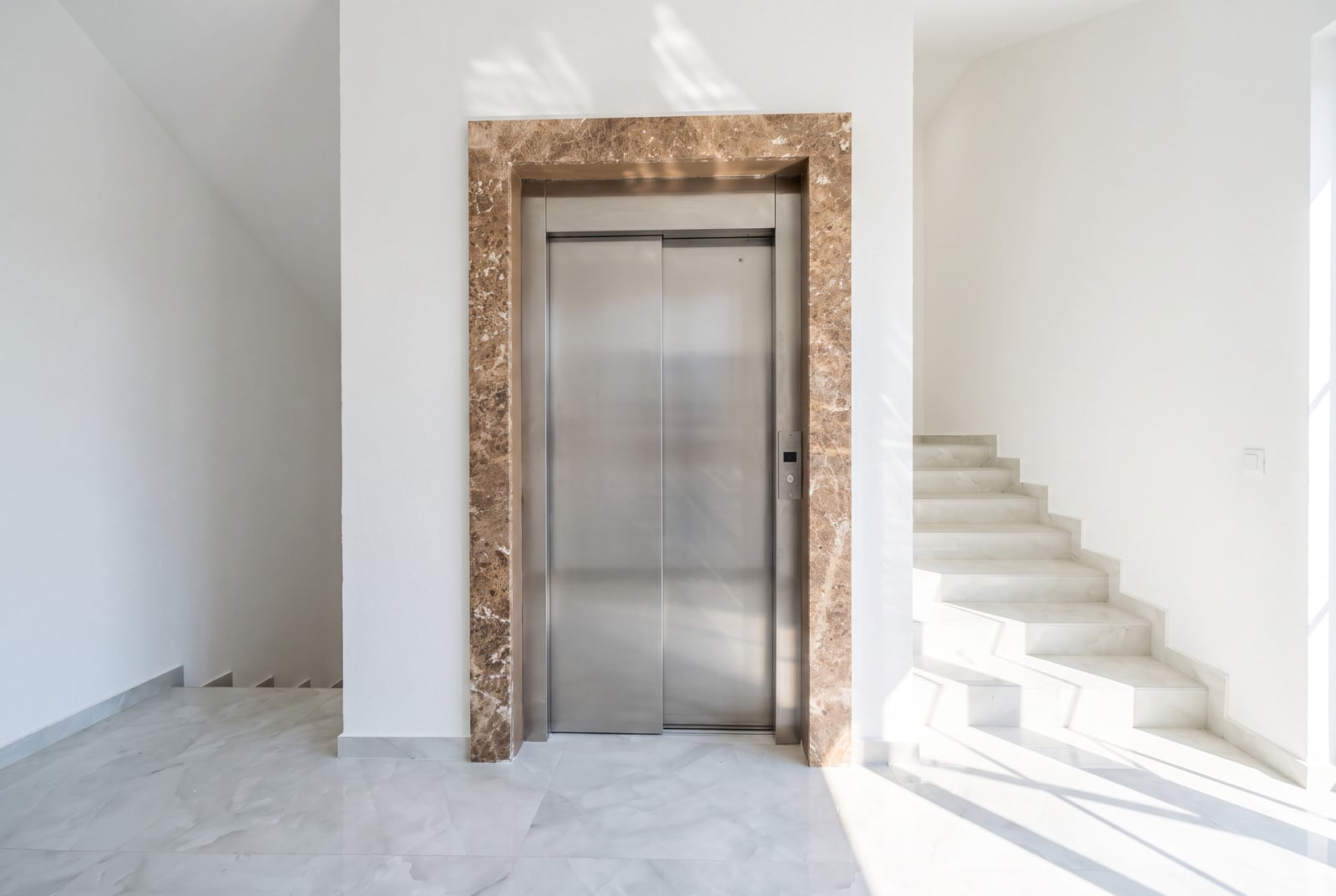 Modern elevator with brown marble finish and white staircase in a residential complex in the city of Bar, Montenegro.