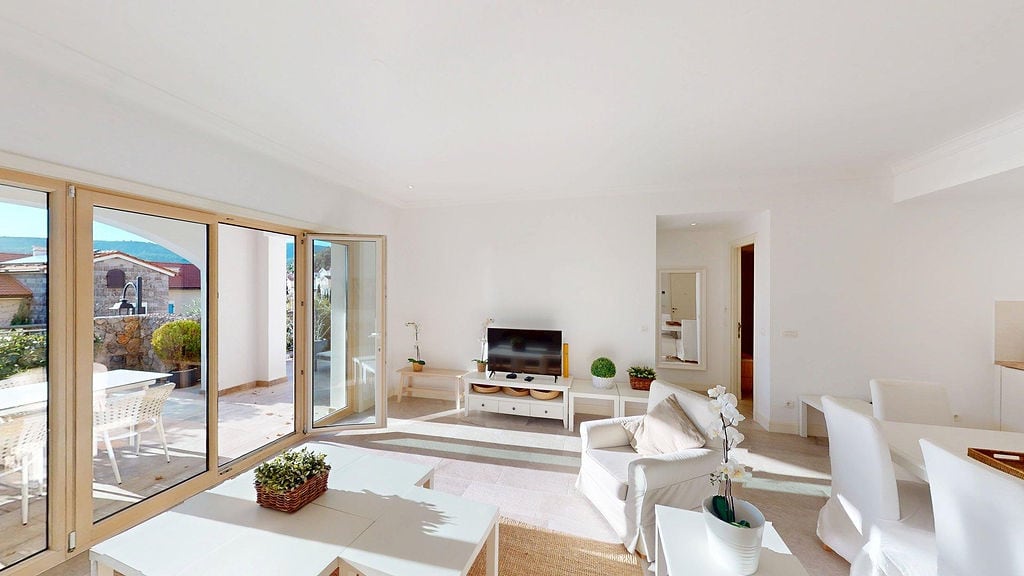 Helles Wohnzimmer mit Panoramafenstern und Zugang zur Terrasse in einer Wohnung, Luštica, Montenegro. Modernes Interieur.