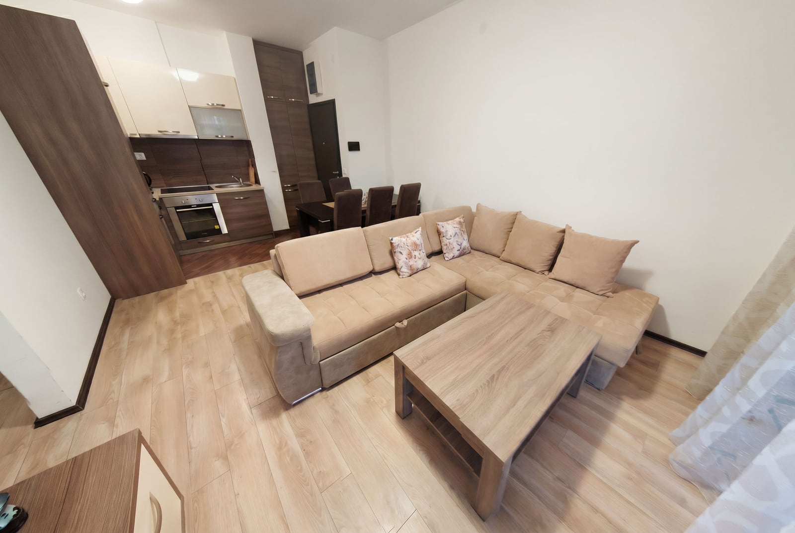 Living room with kitchen in an apartment in Budva, Montenegro: beige corner sofa, dining area, and modern finishes.