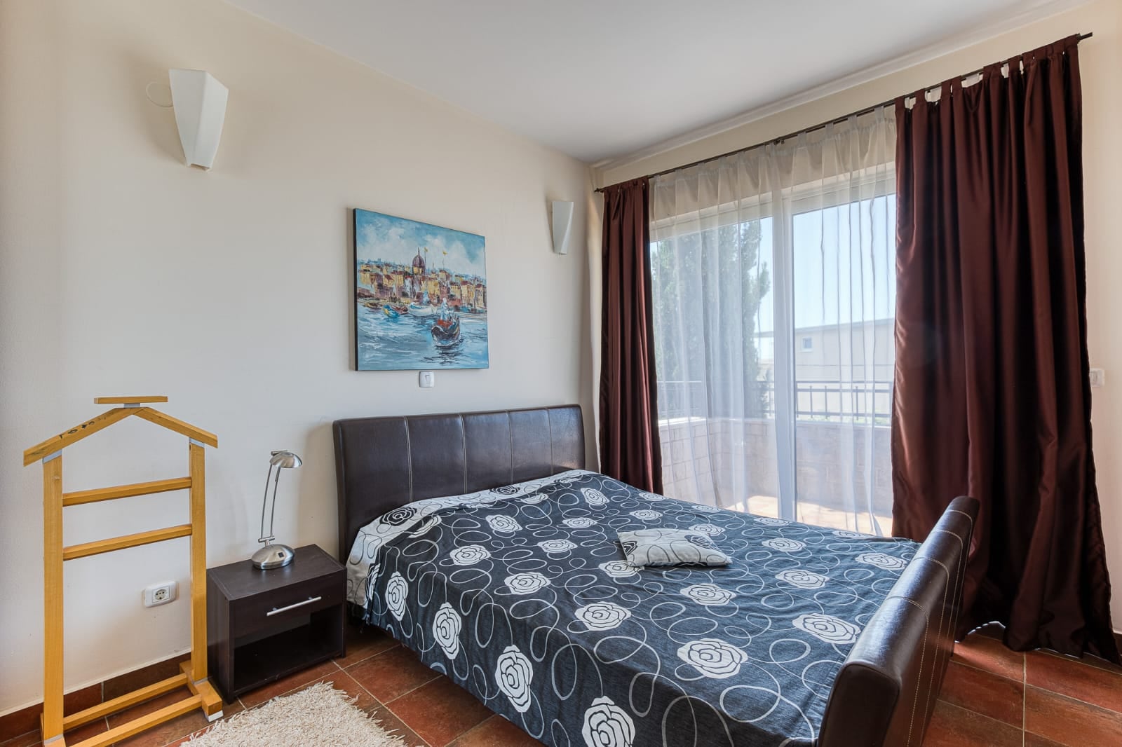Chambre avec lit double et accès à la terrasse dans une villa à Bečići, Monténégro. Intérieur confortable avec un tableau au mur.