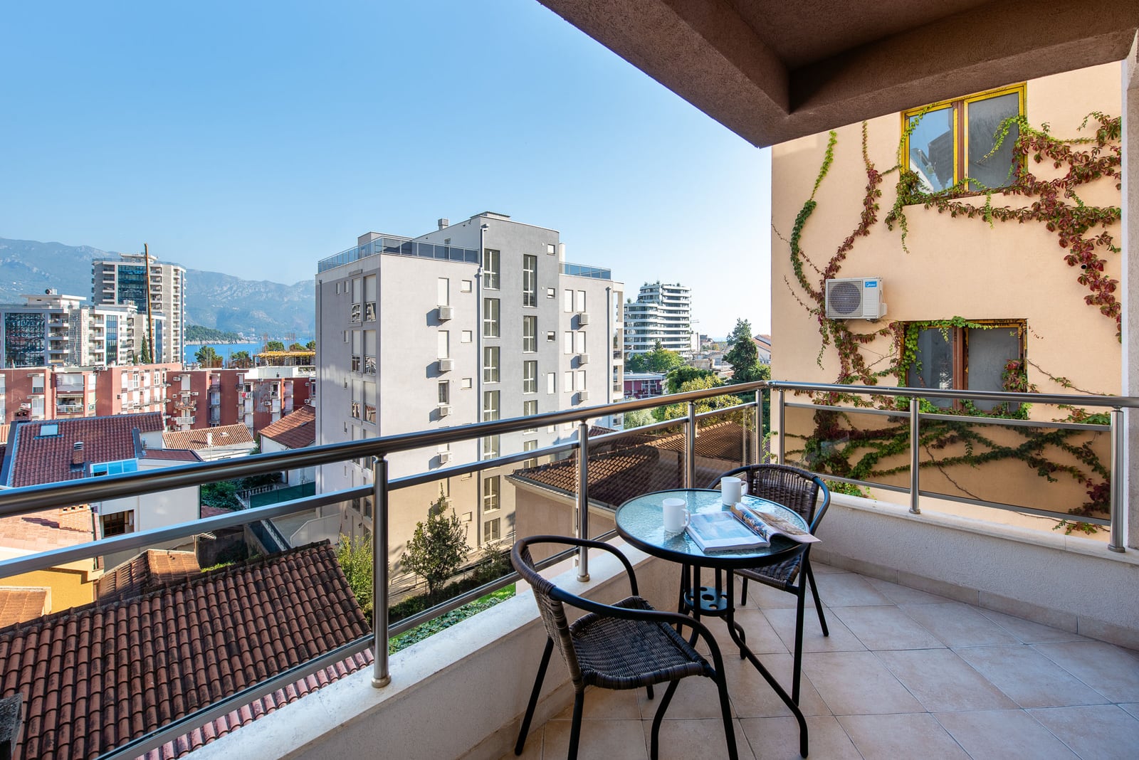 Balcony with furniture and a view of the city and sea in an apartment, Budva, Montenegro. Modern terrace with woven chairs.