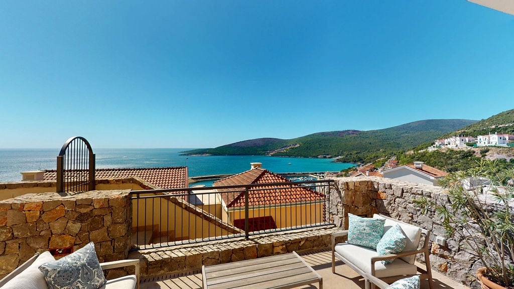 Terasa sa baštenskim nameštajem i panoramskim pogledom na more i planine u stambenom kompleksu Luštica, Crna Gora.