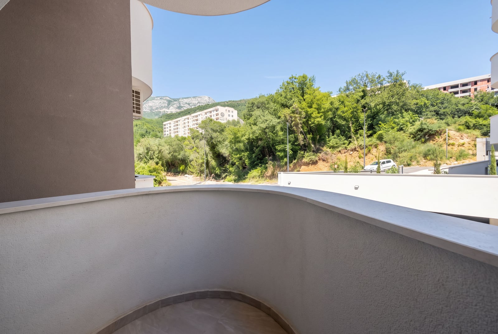 Prostran balkon sa radijusom, bele obrade i pogledom na planine i zelenilo u Bečićima, Crna Gora